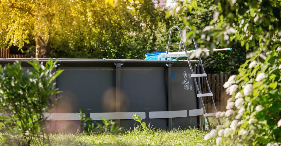 Jardin résidentiel avec piscine hors-sol ronde installée sur pelouse
