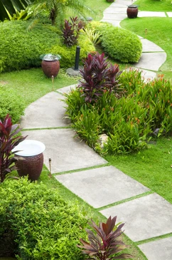 Jardin paysager extérieur avec allée courbe en dalles de béton sur pelouse verte