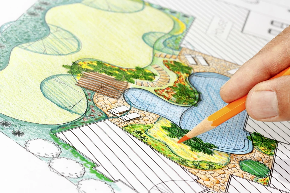 Une personne dessine à la main un plan d'aménagement paysager avec un crayon de couleur orange
