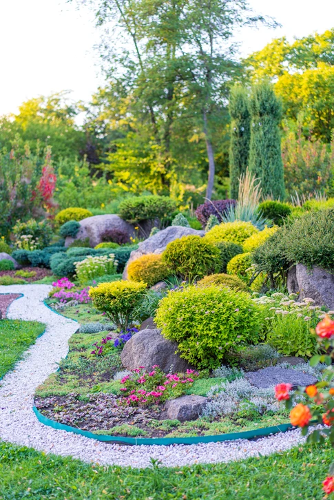 Photographie professionnelle d'un paysagiste ou d'une équipe de paysagistes travaillant activement sur un projet de jardin. L'image montre des professionnels en train de créer ou d'aménager un espace extérieur — par exemple en cours de pose de dallage, de plantation, ou de préparation de massifs. L'ambiance doit transmettre le professionnalisme, la qualité d'exécution et le savoir-faire. Le jardin en arrière-plan doit être soigné et montrer un travail de conception réfléchie. L'image doit capturer l'engagement et la qualification de l'équipe dans la concrétisation d'un projet paysager personnalisé.