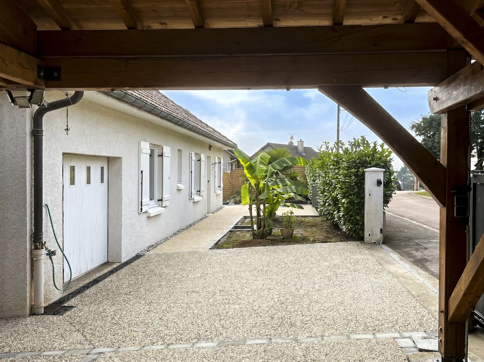 Façade extérieure en pierre naturelle avec porte d'entrée verte à lames horizontales, encadrement blanc, éclairage mural et boîte aux lettres noire